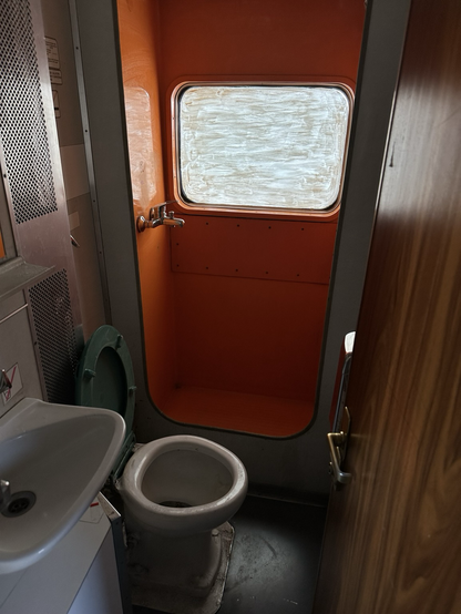 Blick in den Abort des Wagens. Hier hat es in früheren Zeiten mal eine funktionierende Dusche gegeben, wo heute nur noch ein Stummel anstelle des Duschkopfs aus der Wand schaut. Das Fenster ist notdürftig gegen Einsicht von außen verschmiert.