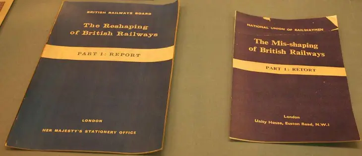 two booklets on a table. the left has a blue cover, is entitled 'The Reshaping of British Railways - Part 1: Report', by the British Railways Board, published by Her Majesty's Stationery Office, the right has a red cover, and is entitled 'The Mis-shaping of British Railways - Part 1: Retort', by the National Union of Railwayment, Unity House, Euston Road, London.

Both covers have, beside the cover text and the color, a striking similarity in formatting.