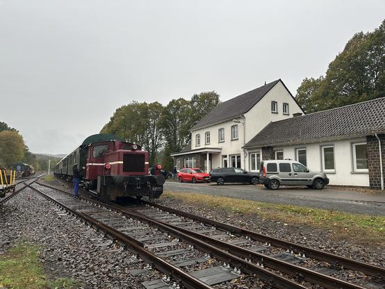 Der Museumszug steht neben dem Bahnhofsgebäude, die Köf im Vordergrund hat bereits die rote Leuchten für den Zugschluss an.