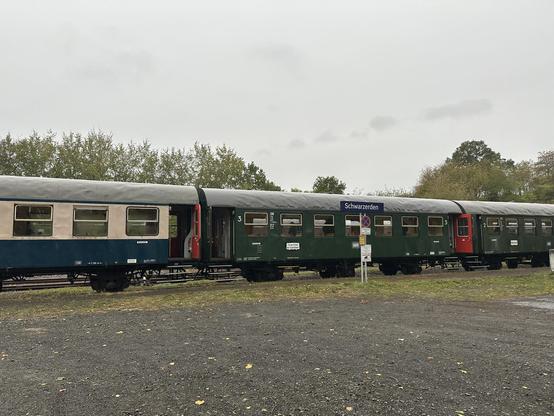 Die Umbau-Dreiachserwagen hinter dem Bahnhofsschild mit Aufschrift "Schwarzerden"