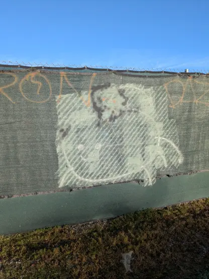 A wall with a graffiti eggbug, painted over but showing through the paint
